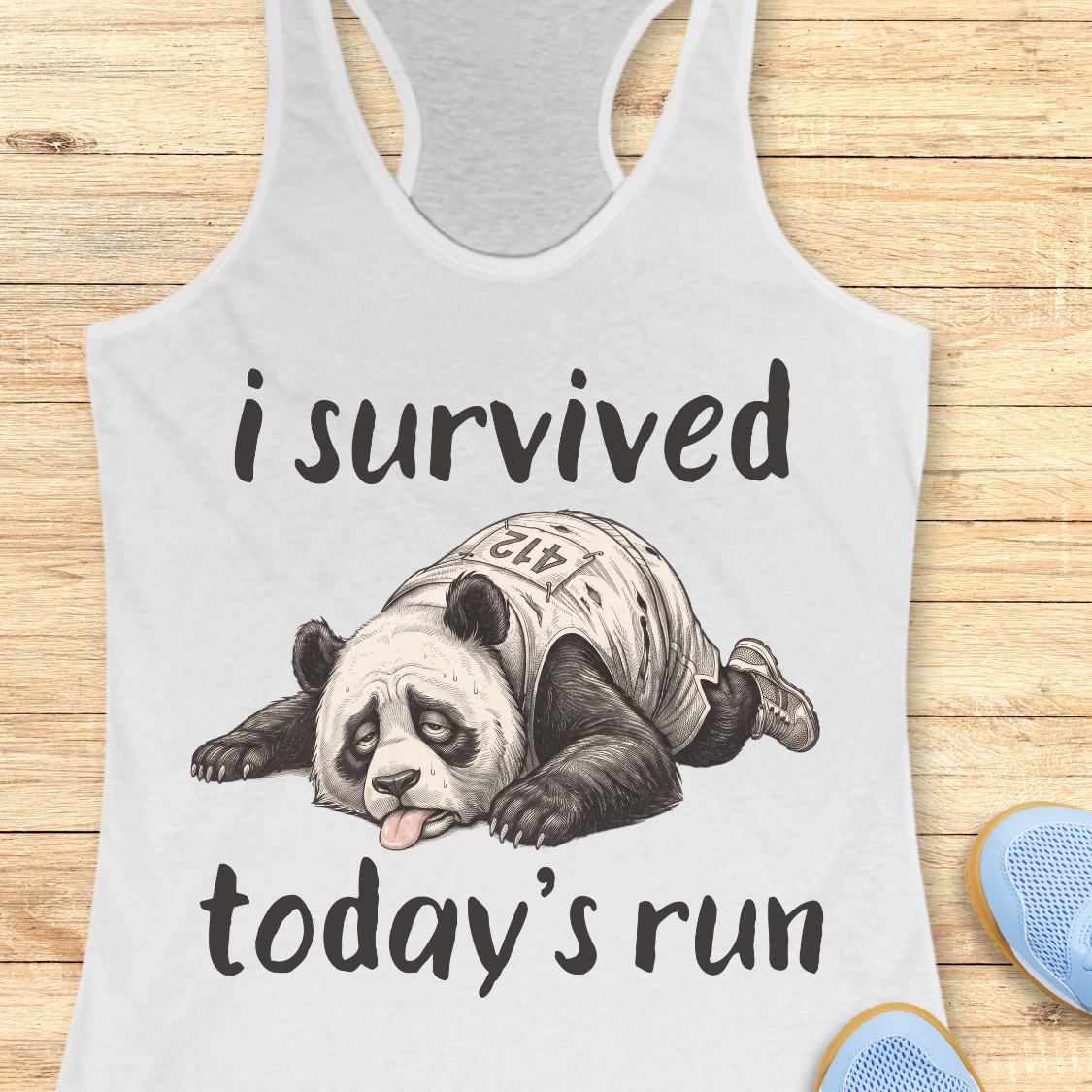A white racerback tank top laid flat on a wooden surface, featuring a humorous graphic of a panda wearing a race bib and the text 'i survived today's run'.