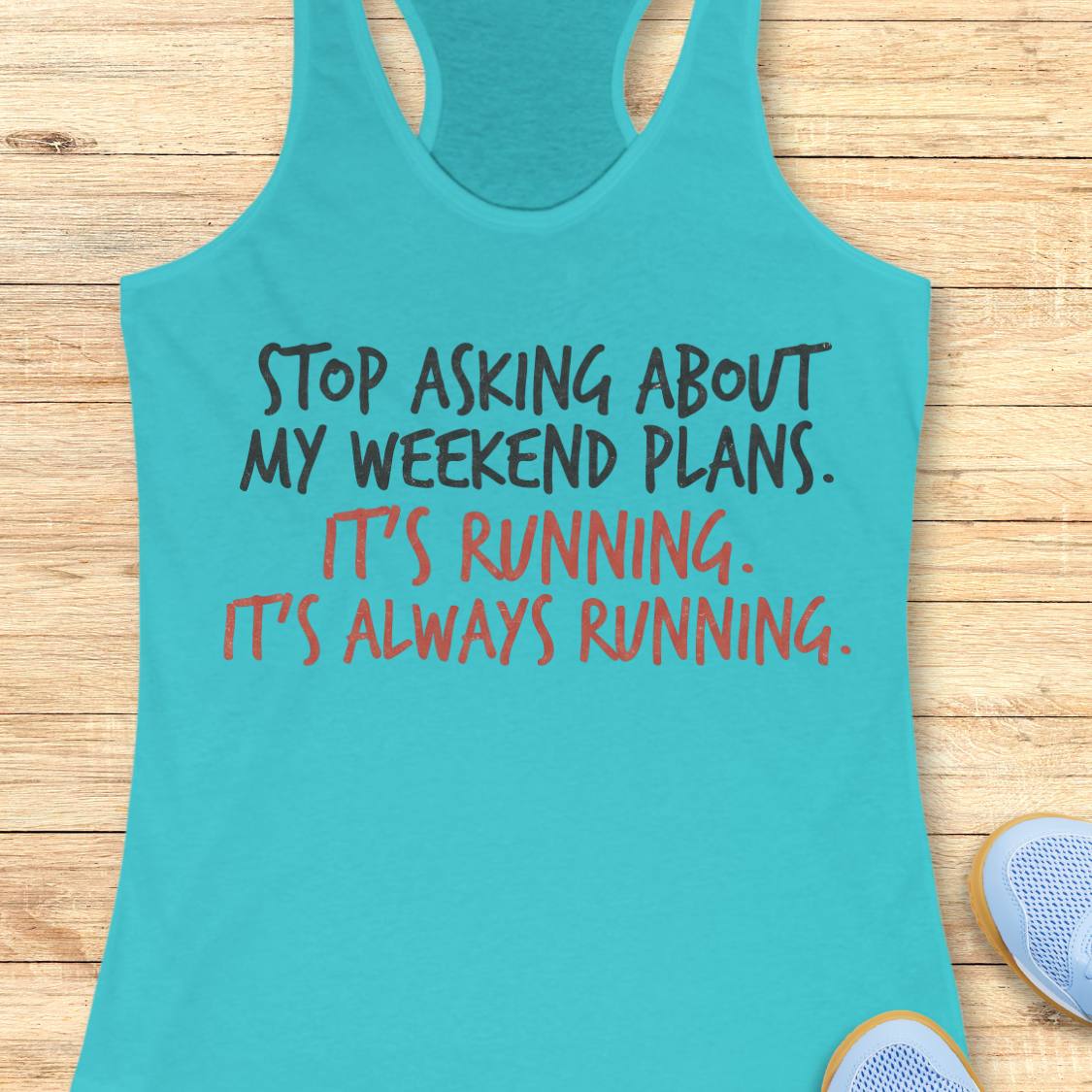 A turquoise racerback tank top laid flat on a light wood floor, with printed text reading 'STOP ASKING ABOUT MY WEEKEND PLANS. IT'S RUNNING.