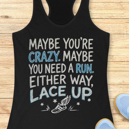 A black racerback tank top laid flat on a light wood background, featuring a motivational graphic that reads 'MAYBE YOU'RE CRAZY. MAYBE YOU NEED A RUN.