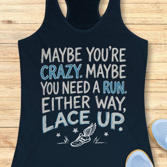 A navy blue racerback tank top with a motivational quote printed on the front, laid flat on a light wood background with partial shoes visible at the edges.