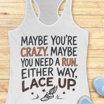 A white racerback tank top laid flat on a light wood background, printed with the motivational phrase “MAYBE YOU’RE CRAZY. MAYBE YOU NEED A RUN.