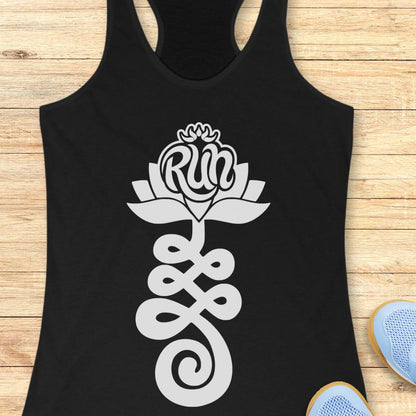 A black racerback tank top with a white graphic of a lotus flower and the word 'Run' integrated into the petals, laid flat on a light wood background with partial blue sneakers visible at the bottom right.