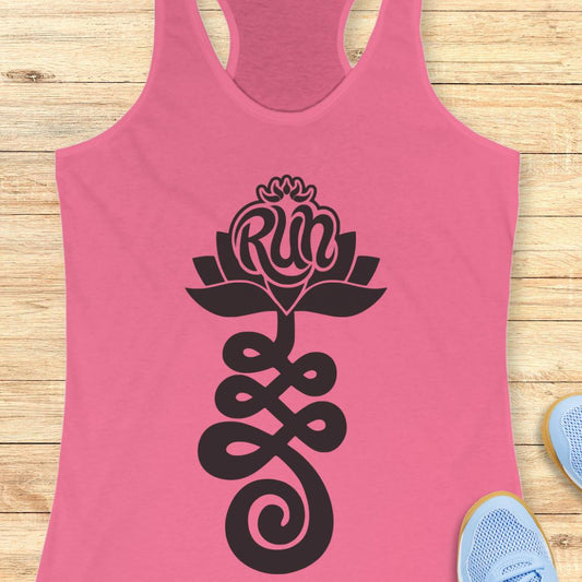 A pink racerback tank top with a black graphic of a lotus flower and the word 'Run' integrated into the petals, laid flat on a light wood background with partial sneakers visible at the edges.