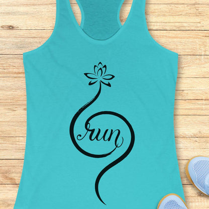 A turquoise racerback tank top with a black script graphic spelling 'run' in a loop, starting from a lotus flower, laid flat on a light wood background with partial sneakers visible at the edges.