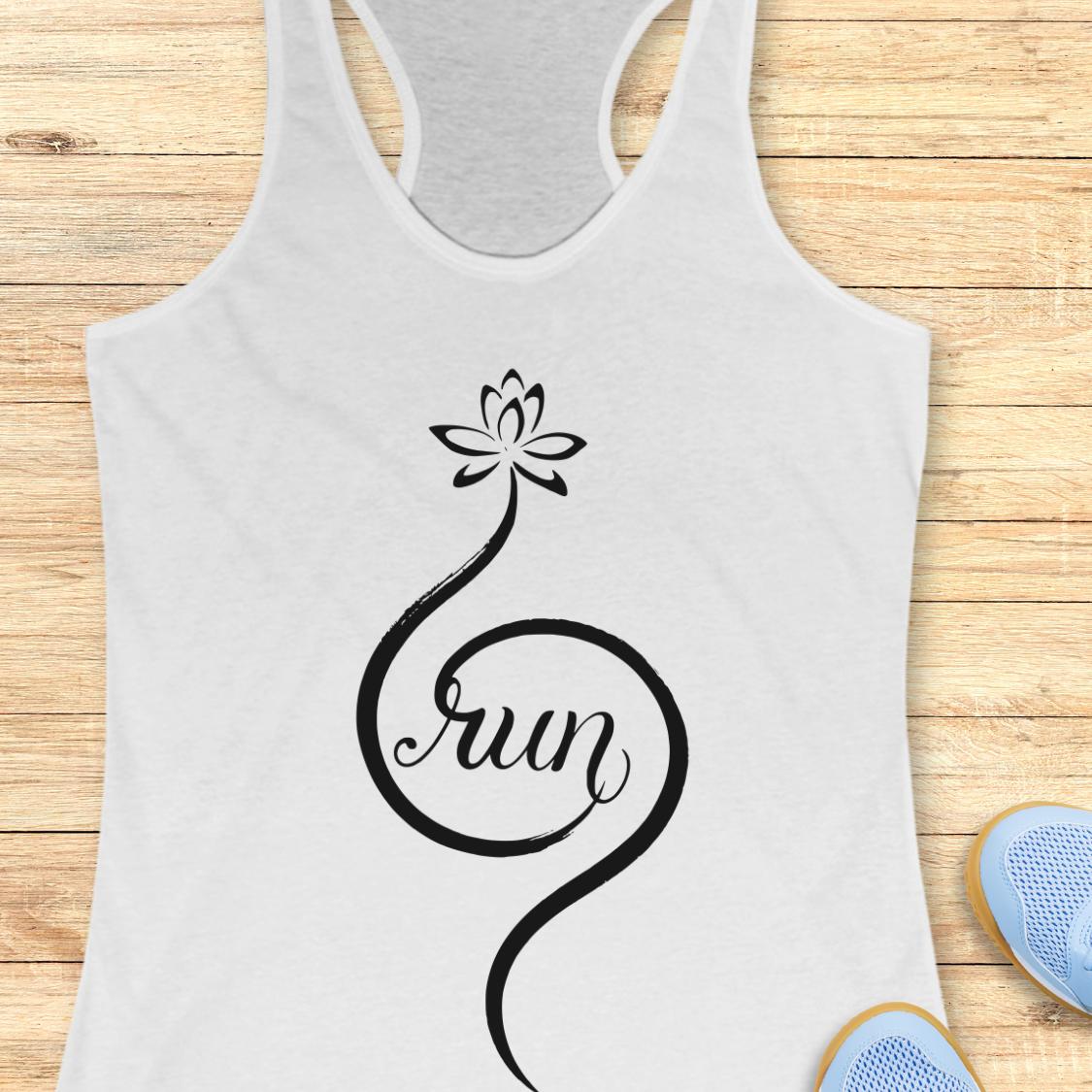 A white racerback tank top with a black lotus flower and the word 'Run' in script, laid flat on a light wood background with partial blue sneakers visible at the bottom right.