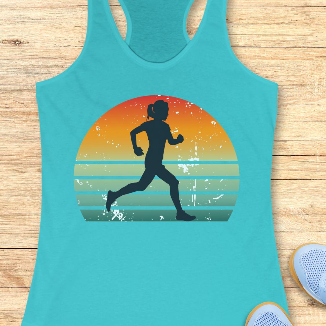 A turquoise racerback tank top laid flat on a light wood surface, featuring a large front graphic of a running silhouette inside a retro sunset circle with orange, yellow, and teal stripes. Partial white sneakers are visible at the bottom right as styling props.