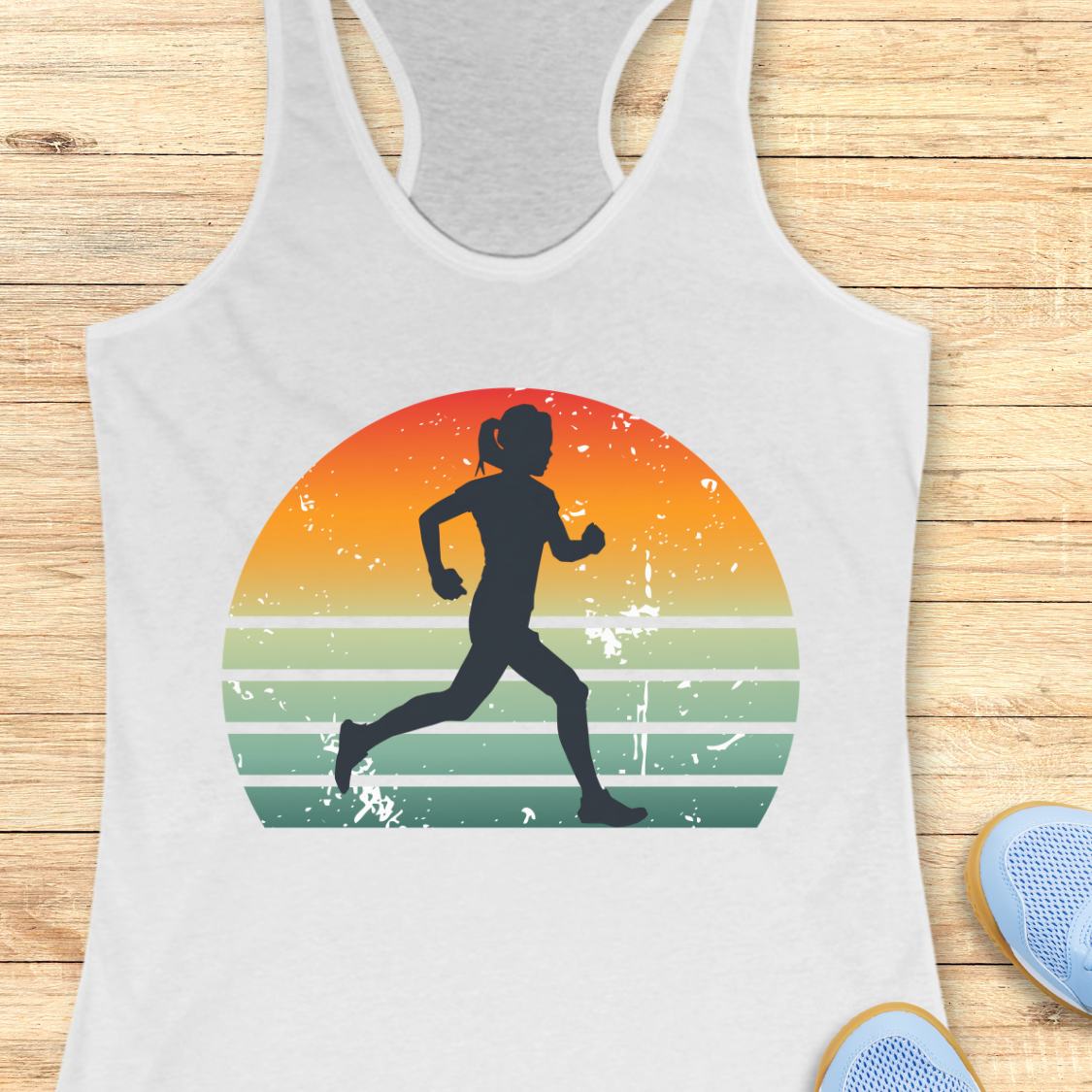 A white racerback tank top laid flat on a light wood surface, featuring a large retro-style graphic of a black running silhouette inside a sunset circle with orange, yellow, green, and blue stripes. Partial blue shoes are visible at the bottom right edge.