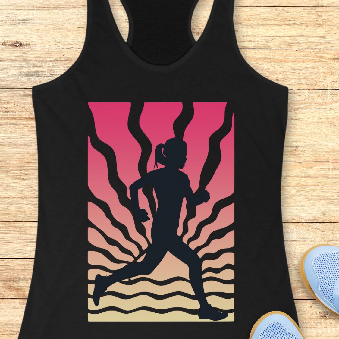 A black racerback tank top laid flat on a light wood surface, featuring a large graphic print of a running silhouette against a pink-to-beige gradient with wavy lines. Part of a blue shoe is visible at the bottom right.