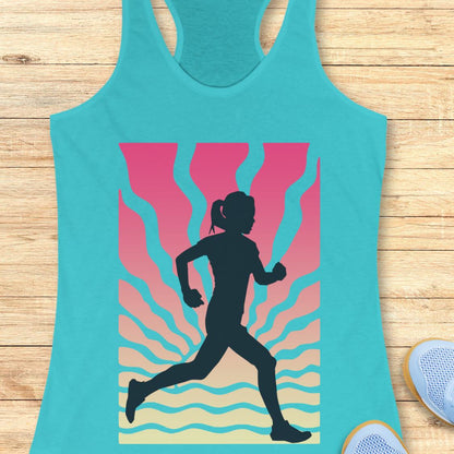 A turquoise racerback tank top laid flat on a light wood background, featuring a large graphic print of a black running silhouette over pink, orange, and beige wavy stripes. Partial light blue sneakers are visible at the bottom right as styling props.