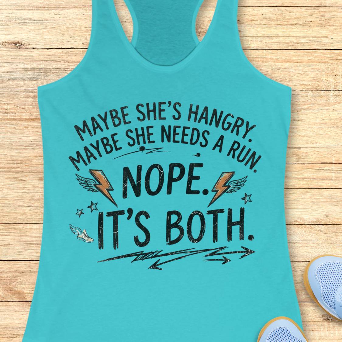 A turquoise racerback tank top laid flat on a light wood floor, featuring a humorous graphic that reads 'MAYBE SHE'S HANGRY. MAYBE SHE NEEDS A RUN.