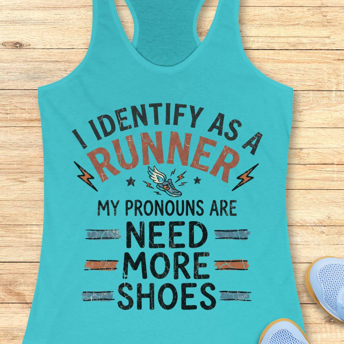 A turquoise racerback tank top laid flat on a light wood surface, featuring a humorous printed slogan about being a runner and needing more shoes. A partial sneaker appears at the bottom right as a styling prop.