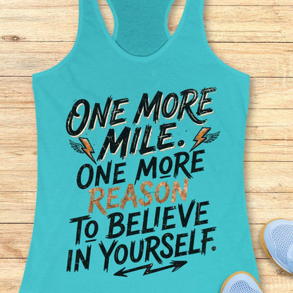 A tahiti blue racerback tank top featuring  the text 'one more mile. one more reason to believe in yourself' printed on the front, displayed flat on a light wood background.