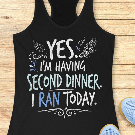A black racerback tank top featuring  the text 'yes. I'm having second dinner. I ran today.' printed on the front, displayed flat on a light wood background.