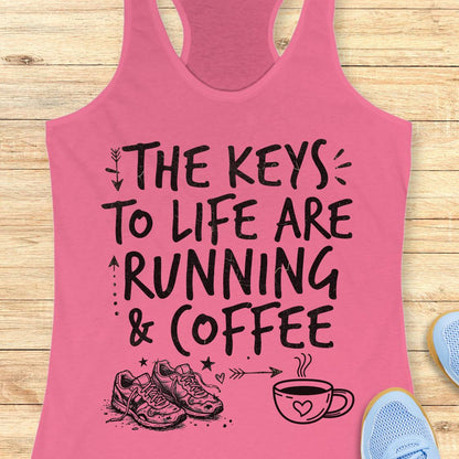 A pink racerback tank top with a black graphic print reading 'THE KEYS TO LIFE ARE RUNNING & COFFEE' with sneakers and a coffee cup illustration, shown on a light wood plank background with partial blue shoes at the edges.