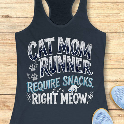 A indigo racerback tank top laid flat on a light wood background, featuring a humorous graphic that reads 'CAT MOM RUNNER REQUIRE SNACKS. RIGHT MEOW' in white and light blue text with paw prints and a small cat illustration.