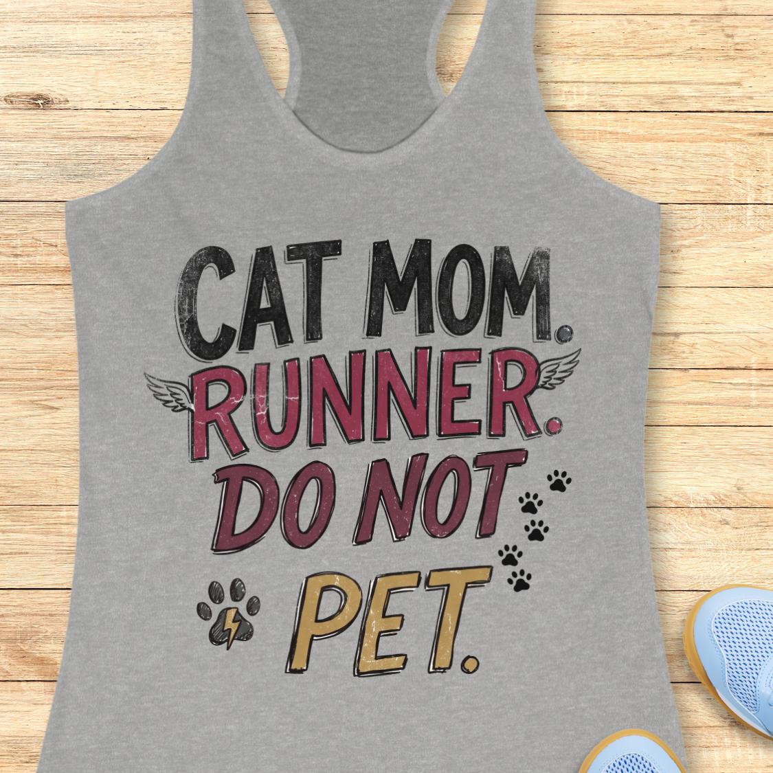 A heather gray racerback tank top laid flat on a light wood surface, featuring the printed phrase 'CAT MOM. RUNNER.