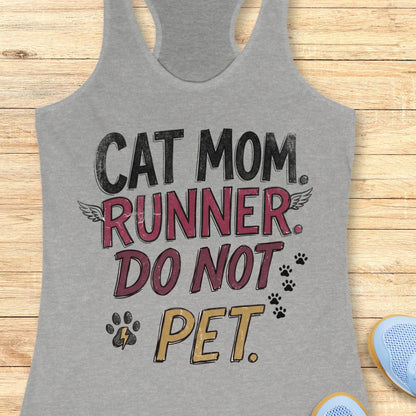 A heather gray racerback tank top laid flat on a light wood surface, featuring the printed phrase 'CAT MOM. RUNNER.