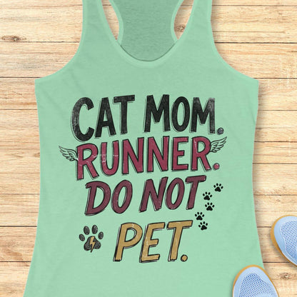 A mint green racerback tank top laid flat on a light wood background, featuring a graphic print that reads 'CAT MOM. RUNNER.