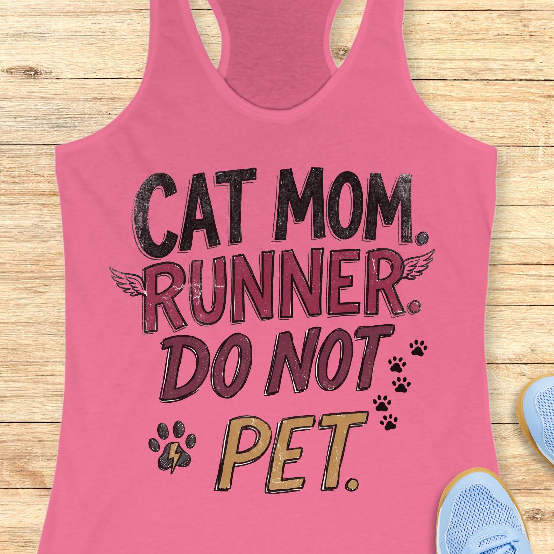 A pink racerback tank top laid flat on a light wood surface, featuring the text 'CAT MOM. RUNNER.