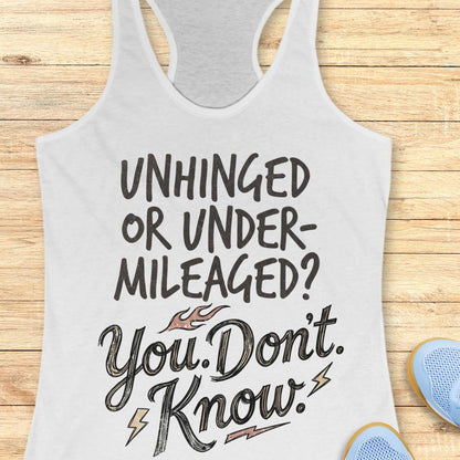 A white racerback tank top with a graphic text print reading 'UNHINGED OR UNDER-MILEAGED? You Don't. Know.