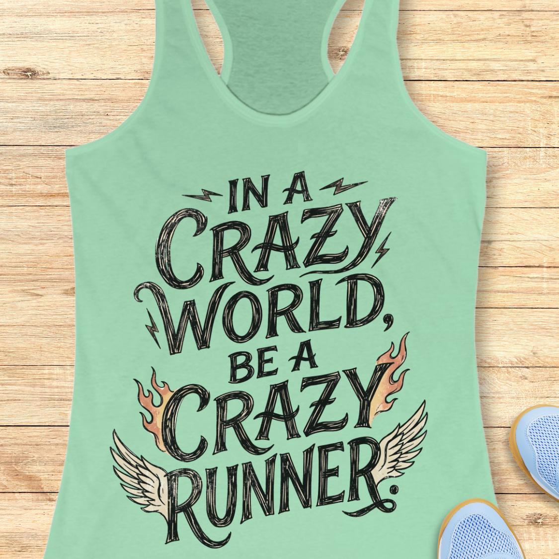 A mint green racerback tank top laid flat on a light wood plank background, featuring the graphic text 'IN A CRAZY WORLD, BE A CRAZY RUNNER' with black lettering, flame motifs, and wing details. Partial blue sneakers are visible at the bottom right as styling props.