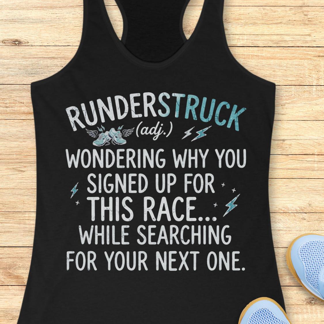 A black racerback tank top laid flat on a light wood surface, featuring a humorous white and light blue graphic that reads 'RUNDERSTRUCK (adj.) WONDERING WHY YOU SIGNED UP FOR THIS RACE.