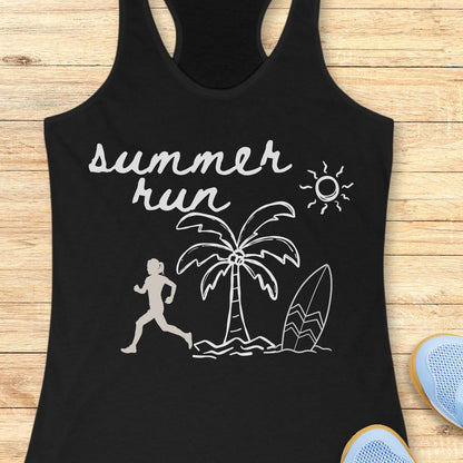 A black racerback tank top with a white graphic print that reads 'summer run' above a running figure, palm tree, surfboard, and sun, laid flat on a light wood background with partial blue shoes visible at the edges.