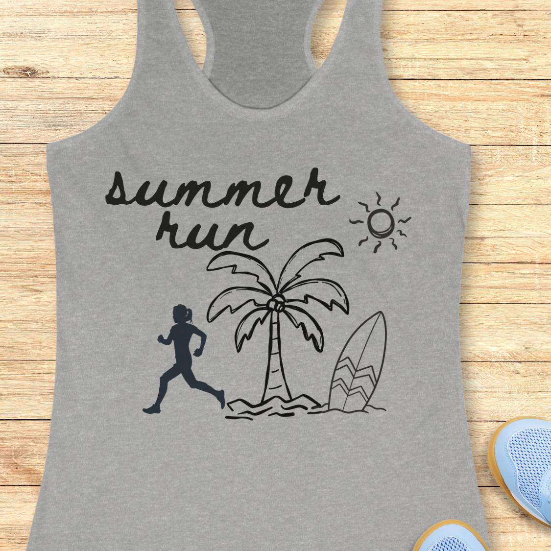 A heather gray racerback tank top laid flat on a light wood background, featuring a black graphic print that reads 'summer run' above a running figure, palm tree, surfboard, and sun. Partial blue shoes are visible at the bottom right as styling props.