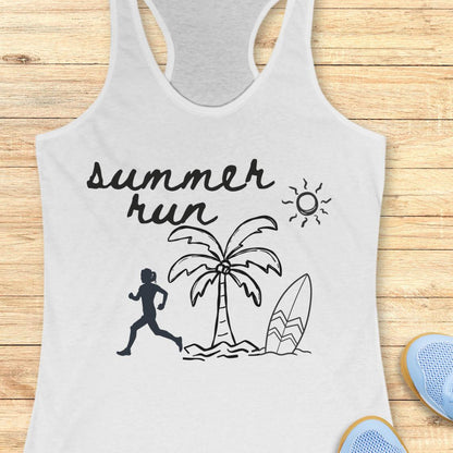 A white racerback tank top with a black 'summer run' graphic featuring a running silhouette, palm tree, surfboard, and sun, displayed flat on a light wood background with blue sneakers partially visible.