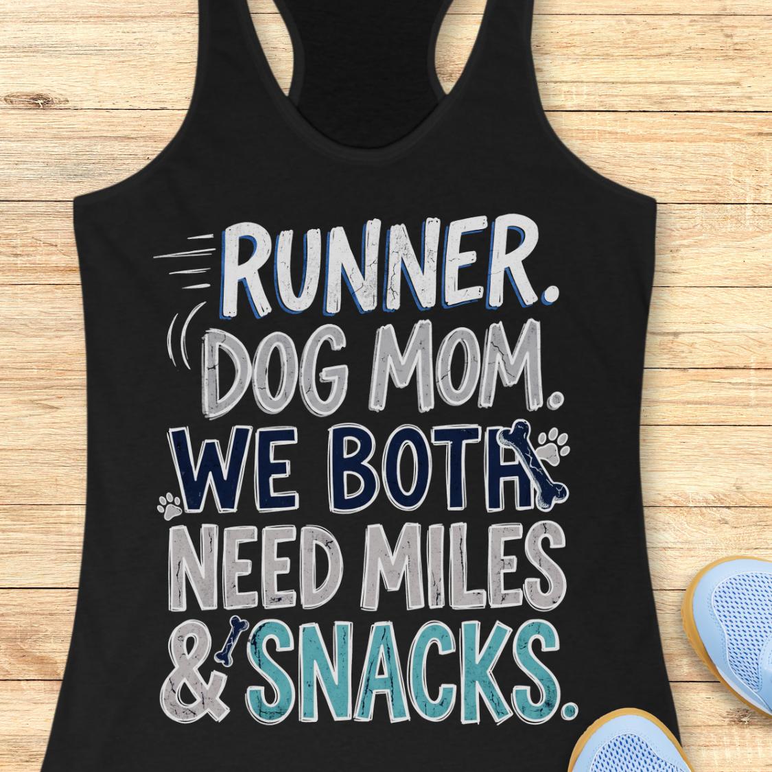 A black racerback tank top laid flat on a light wood background, featuring the text 'RUNNER. DOG MOM.