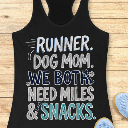 A black racerback tank top laid flat on a light wood background, featuring the text 'RUNNER. DOG MOM.