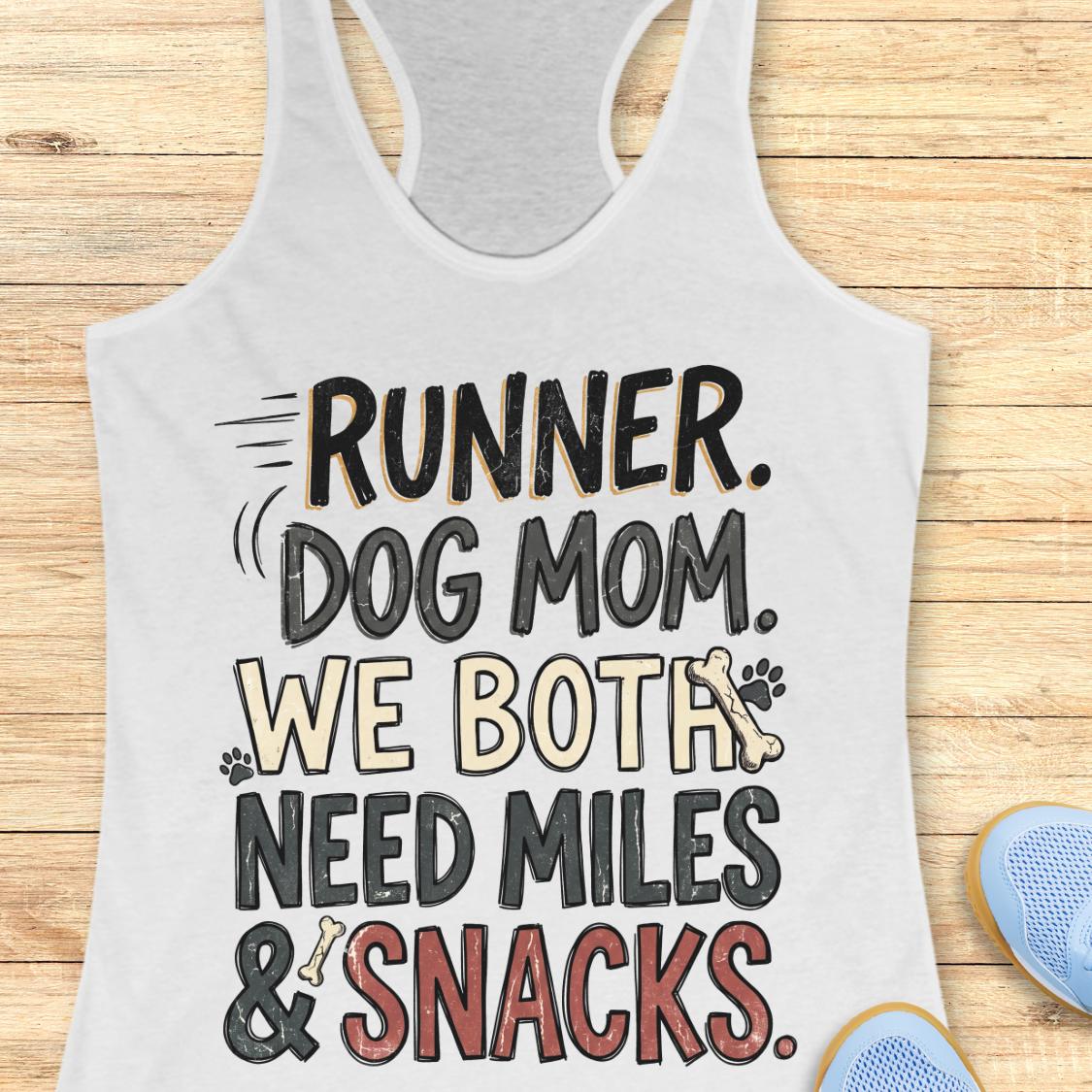 A white racerback tank top laid flat on a light wood background, featuring a humorous graphic that reads 'RUNNER. DOG MOM.