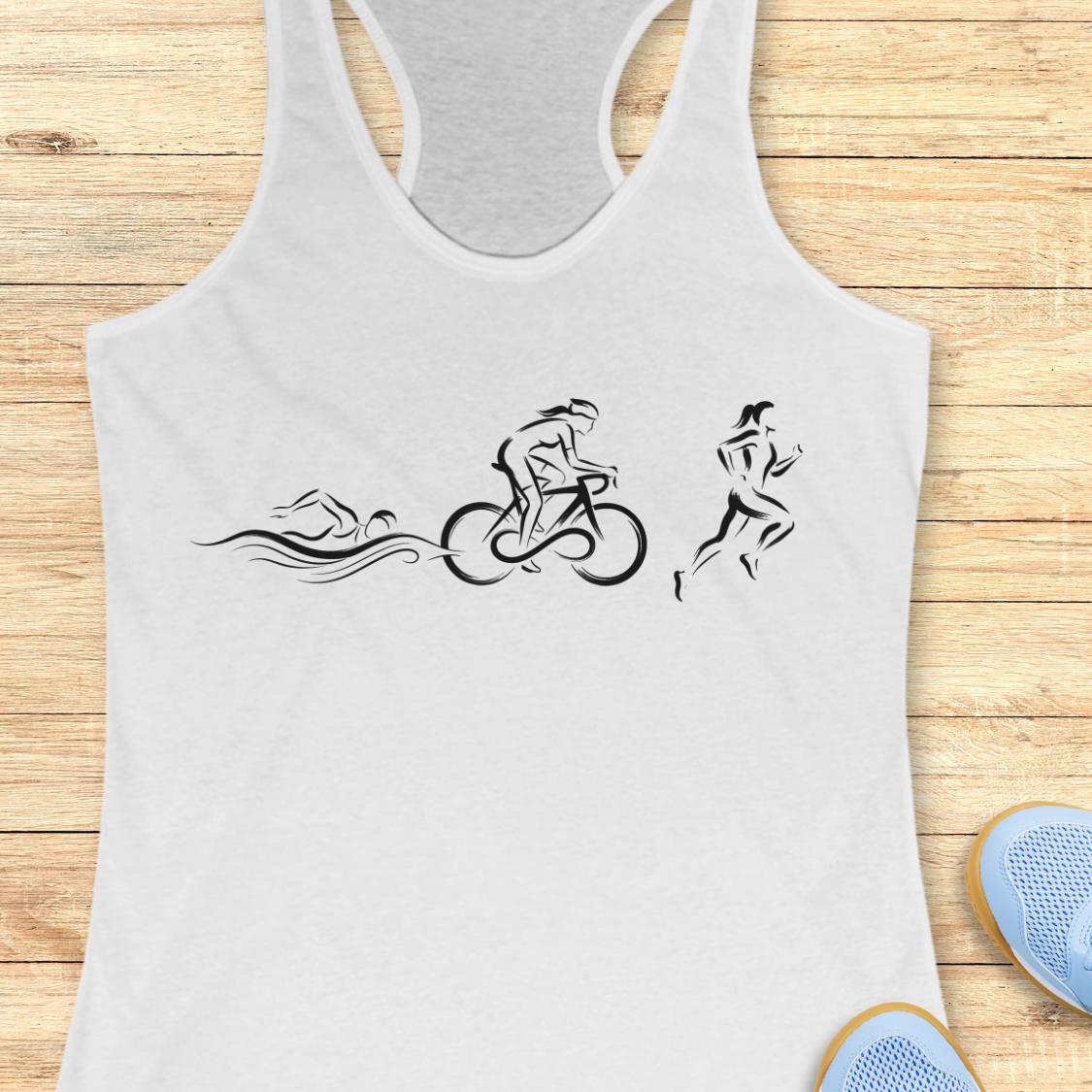 A white racerback tank top laid flat on a light wood background, featuring a black line art graphic of a swimmer, cyclist, and runner. Partial blue shoes are visible at the bottom right as styling props.