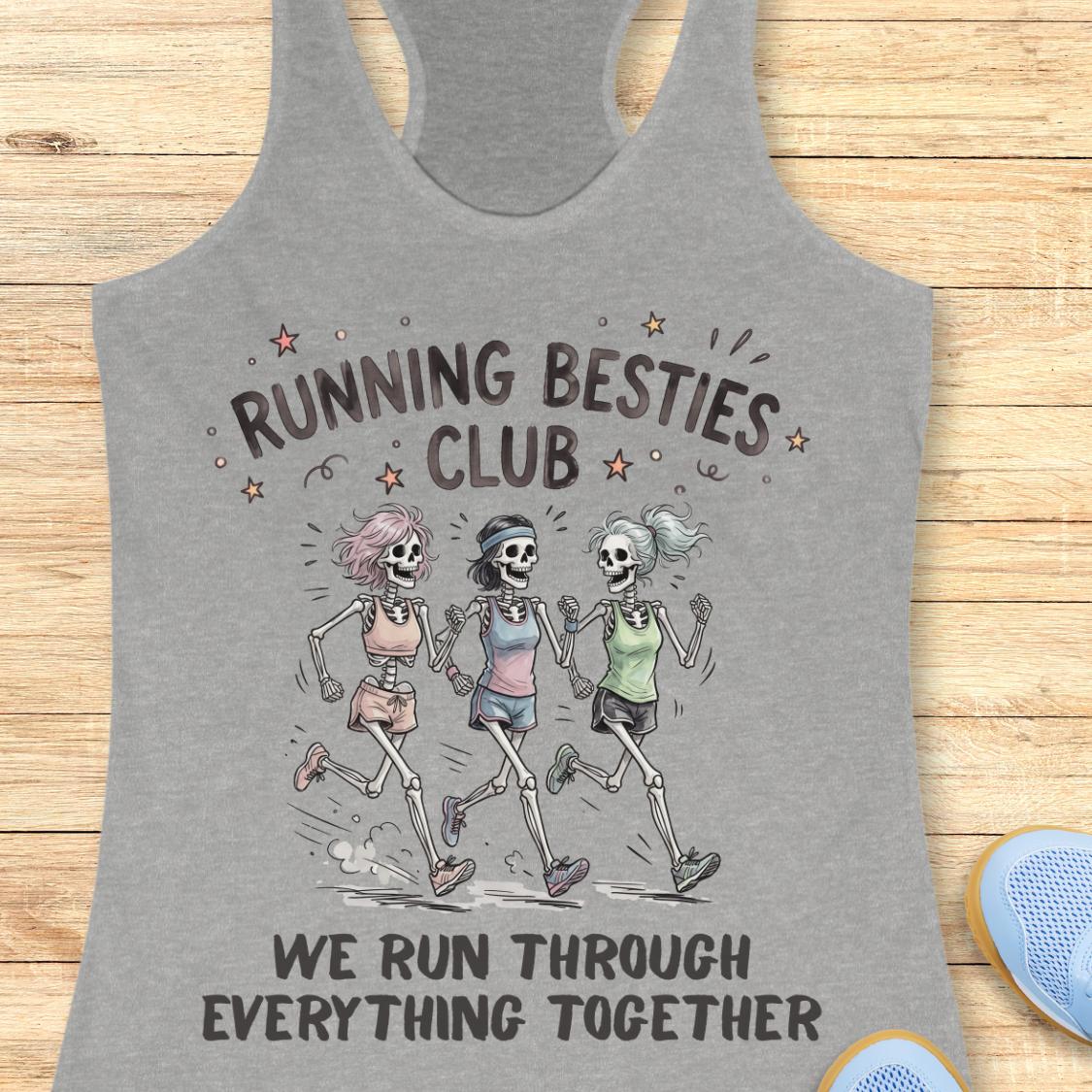 A heather gray racerback tank top laid flat on a light wood surface, featuring a printed graphic of three cartoon skeletons running together with the text 'RUNNING BESTIES CLUB' and 'WE RUN THROUGH EVERYTHING TOGETHER.' A partial blue shoe is visible at the lower right edge.