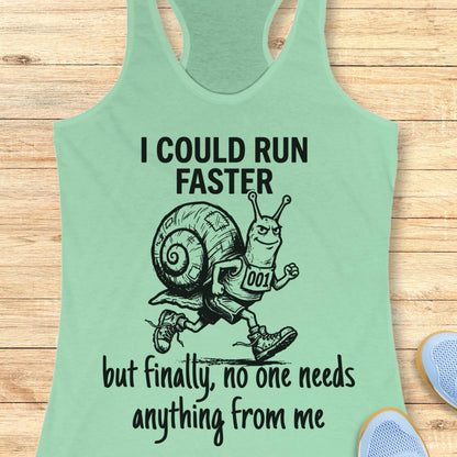 A mint green racerback tank top laid flat on a light wood background, featuring a black graphic of a snail running with the text 'I COULD RUN FASTER but finally, no one needs anything from me'.