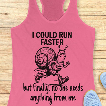 A pink racerback tank top laid flat on a light wood background, featuring a black graphic of a snail running with the text 'I COULD RUN FASTER but finally, no one needs anything from me'.