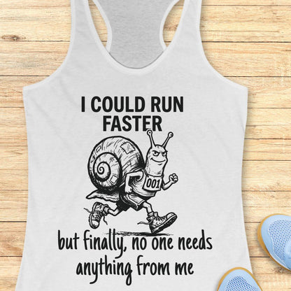 A white racerback tank top with a black graphic of a snail running and the text 'I COULD RUN FASTER but finally, no one needs anything from me', shown on a wooden background with blue shoes partially visible in the corner.