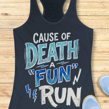 A indigo racerback tank top laid flat on a light wood background, featuring a distressed graphic that reads 'CAUSE OF DEATH A "FUN" RUN' in white and blue lettering. Part of a light blue shoe is visible at the bottom right as a styling prop.