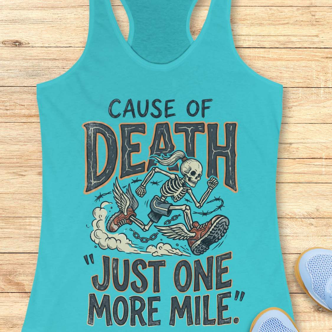 A turquoise racerback tank top laid flat on a light wood surface, featuring a graphic of a skeleton running with a shoe and the text 'CAUSE OF DEATH "JUST ONE MORE MILE".' A partial blue shoe is visible at the bottom right as a styling prop.