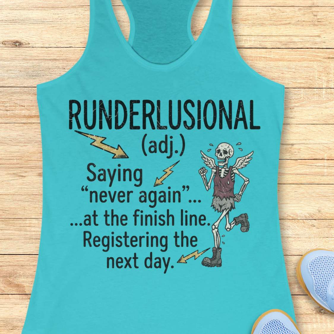 A turquoise racerback tank top laid flat on a light wood surface, featuring a humorous graphic with the text 'RUNDERLUSIONAL (adj.) Saying "never again" .