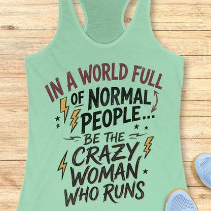 A mint green racerback tank top with a motivational graphic printed on the front, laid flat on a light wood background with a sneaker partially visible in the corner.