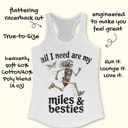 A white racerback tank top laid flat on a light wood background, featuring a colorful graphic that reads 'all I need are my miles & besties' with a running female skeleton. Part of a blue shoe is visible at the bottom right.