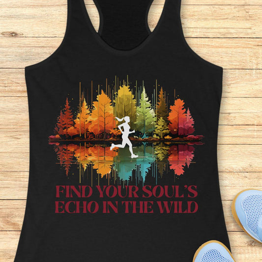 A black racerback tank top laid flat on a light wood background, featuring a colorful forest graphic with a white running silhouette and the text 'FIND YOUR SOUL'S ECHO IN THE WILD' in red. Part of a blue shoe is visible at the bottom right.