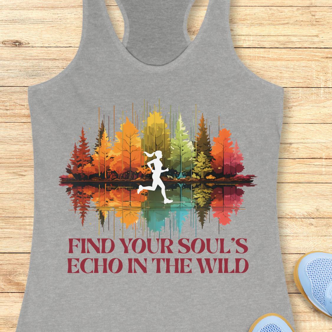 A heather gray racerback tank top laid flat on a light wood background, featuring a colorful graphic of a runner in front of autumn trees reflected in water, with the text 'FIND YOUR SOUL'S ECHO IN THE WILD' below.