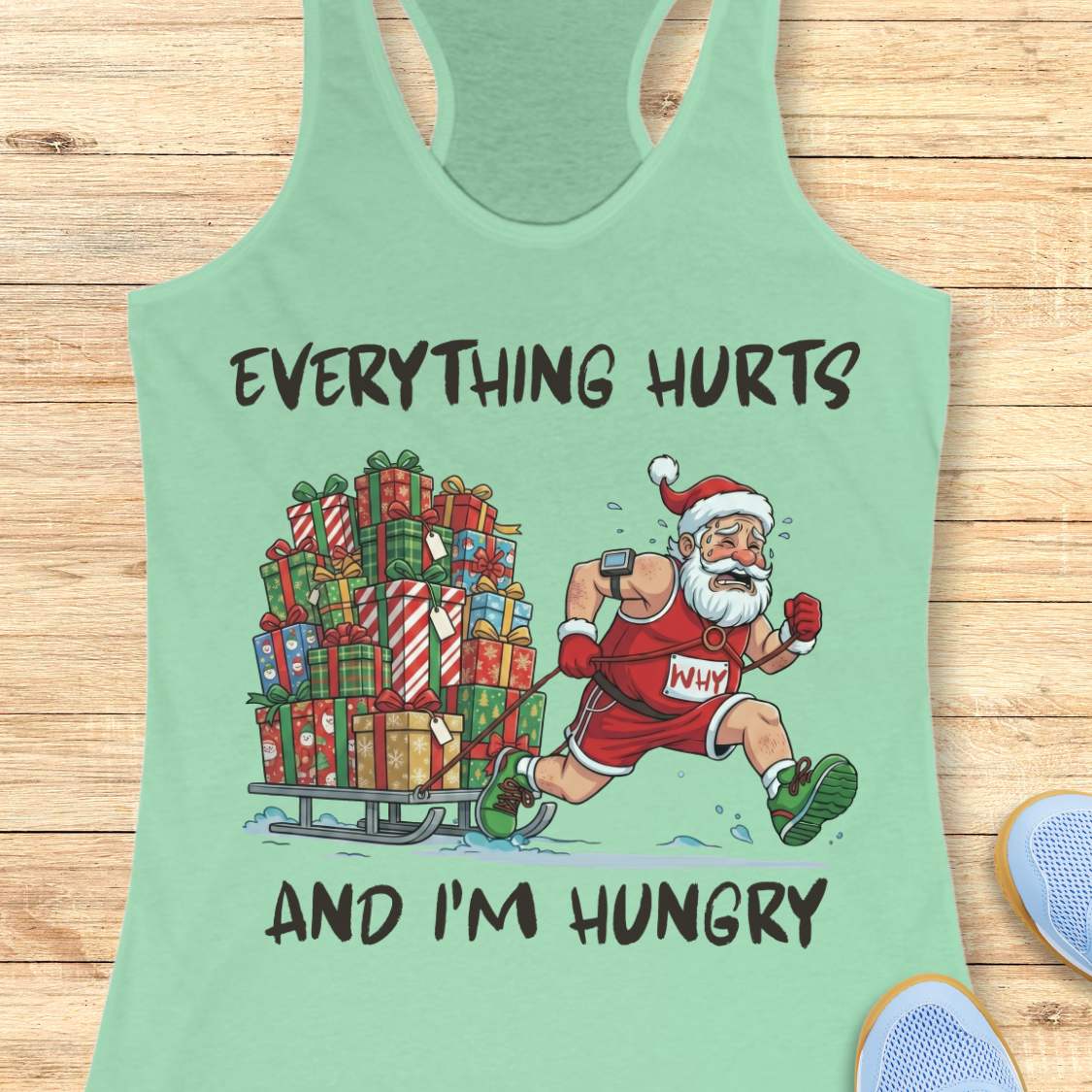Funny Christmas running design on a mint-green tank top featuring a cartoon Santa Claus running while pulling a sled piled high with wrapped Christmas presents. Bold black text above and below the illustration reads: "EVERYTHING HURTS AND I'M HUNGRY." The festive artwork combines holiday humor with running and fitness themes.