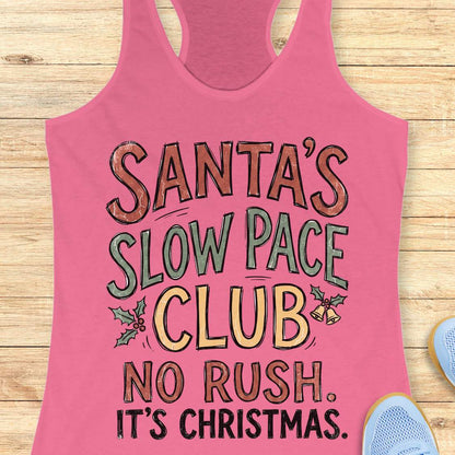 A pink racerback tank top with a festive graphic reading 'SANTA'S SLOW PACE CLUB NO RUSH. IT'S CHRISTMAS.