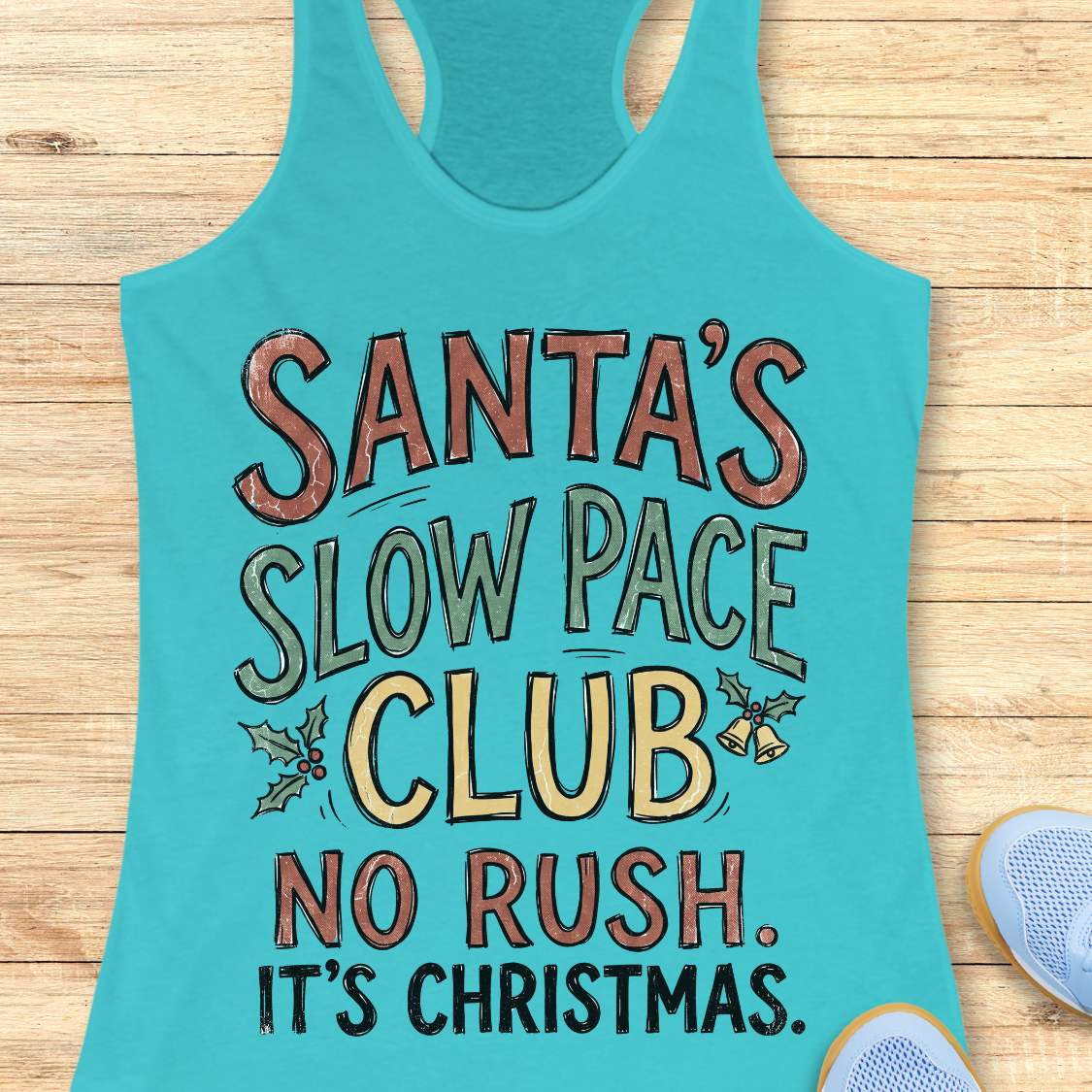 A turquoise racerback tank top with a festive graphic reading 'SANTA'S SLOW PACE CLUB NO RUSH. IT'S CHRISTMAS.