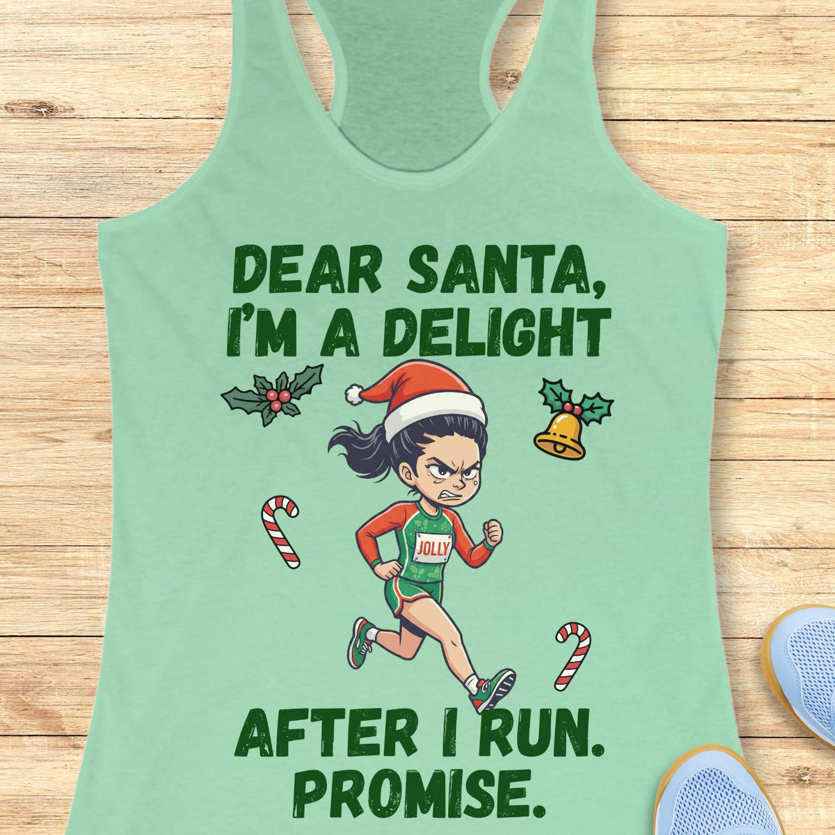 mint green racerback tank top displayed on a light wooden surface, featuring a festive running-themed graphic. The design shows a cartoon runner wearing a Santa hat, green running outfit with the word “JOLLY” on the chest, and running shoes. Holiday elements including holly leaves, a Christmas bell, and candy canes surround the runner. Bold green text above and below the illustration reads: “DEAR SANTA, I’M A DELIGHT” and “AFTER I RUN. PROMISE.” Partial blue athletic shoes are visible in the lower corners