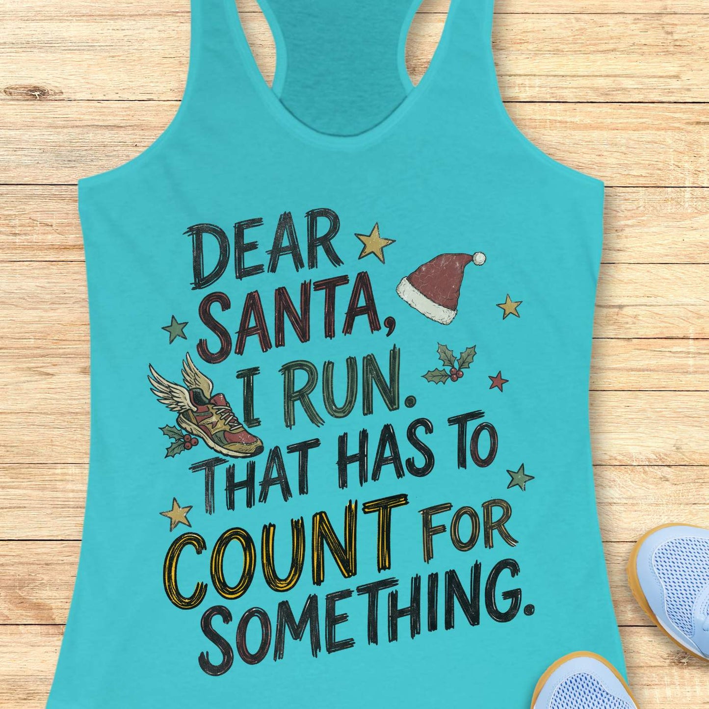 Tahiti blue racerback tank top displayed on a light wooden surface, featuring a festive running-themed typographic design. The graphic includes the humorous text: “DEAR SANTA, I RUN. THAT HAS TO COUNT FOR SOMETHING.” Decorative holiday elements surround the text, including a red Santa hat, a winged running shoe, holly sprigs with berries, and colorful stars. The word “COUNT” is highlighted in yellow, while the remaining text appears in black. Partial blue athletic shoes are visible in the lower corners, rei