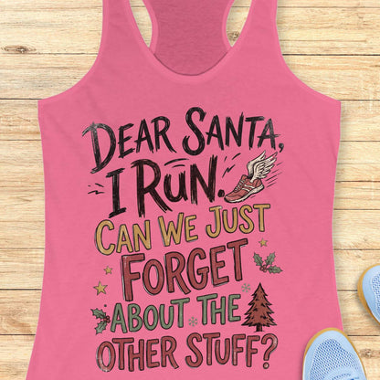 pink racerback tank top displayed on a light wooden surface, featuring a festive running-themed typography design. The graphic includes the humorous text: “DEAR SANTA, I RUN. CAN WE JUST FORGET ABOUT THE OTHER STUFF?” Decorative holiday accents surround the text, including a winged running shoe, holly sprigs with red berries, gold stars, snowflakes, and a Christmas tree. The design uses black, red, green, and gold lettering for a playful holiday look. Partial blue athletic shoes are visible in the lower co
